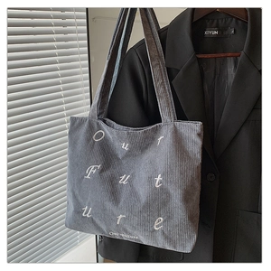 Close-up of grey corduroy tote bag featuring white Our Future embroidery and ribbed texture