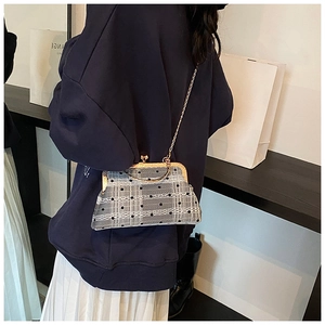 Detail of grey plaid shell bag with black dots, white lace trim and gold chain strap