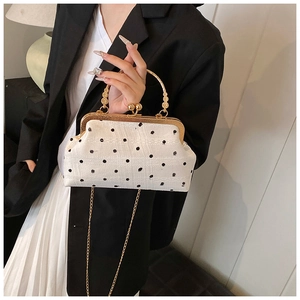 White vintage shell bag with black polka dots, gold ring handle and chain strap details