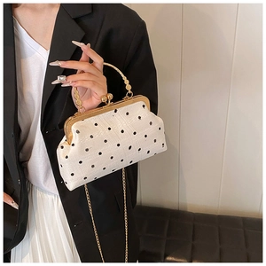 Detailed view of vintage polka dot shell bag with gold metal frame and carved handle