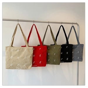 Detailed view of corduroy tote bags with Our Future embroidery in multiple colors