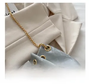 Detail of grey ripple texture bucket bag with gold eyelets and thick chain strap