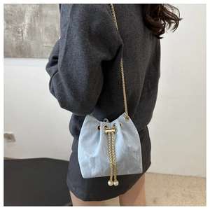 Détail du sac seau bleu clair avec texture plissée et cordons ornés de perles