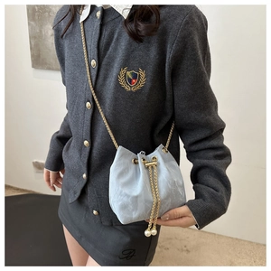 Détail du sac seau bleu clair avec chaîne dorée et perles élégantes sur le cordon