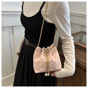 Detailed view of pink bucket bag with gold chain strap and large pearl charms on drawstring
