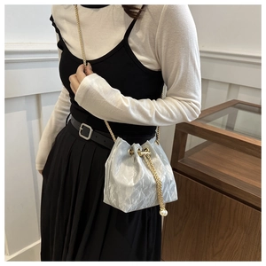 Détail du sac seau argenté avec bandoulière chaîne dorée et grande perle décorative