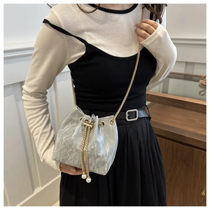 Close-up of silver pleated bucket bag with gold chain strap and pearl charms