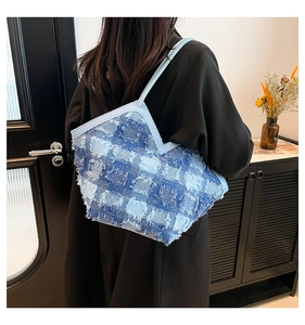 Détail du sac seau en denim patchwork bleu avec bords effilochés et fine bandoulière