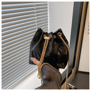 Gros plan du sac seau en velours noir avec chaîne dorée et détails perles