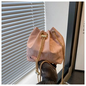Détail du sac seau rose plissé avec chaîne dorée et breloques de cordon en perles