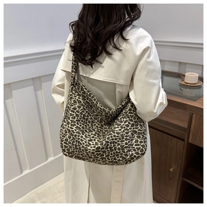 Vue détaillée d'un grand sac hobo en toile léopard porté avec un trench-coat beige chic