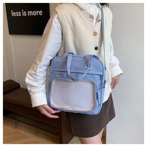 Detail of blue nylon tote bag with mesh pocket and adjustable strap worn by a model