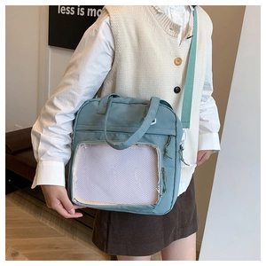 Detail of light blue tote bag with transparent mesh pocket and adjustable green strap
