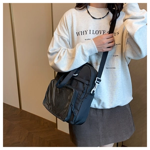 Detail of black crossbody tote with clear front pocket and adjustable fabric strap