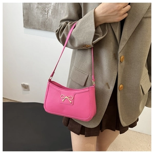 Pink baguette shoulder bag with gold bow detail, styled with casual suit for women