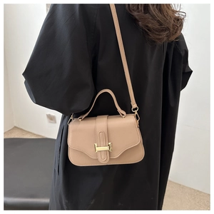 Close-up of beige shoulder bag with H-shaped gold buckle and lychee leather texture