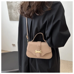 Close-up of light brown leather crossbody bag with a distinctive gold metal buckle