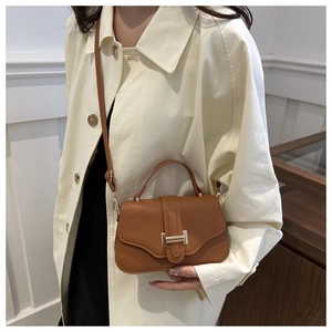 Detailed view of caramel brown lychee leather texture and gold metal clasp on shoulder bag