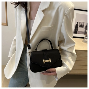 Close-up of black litchi pattern square bag with elegant gold clasp and shoulder strap