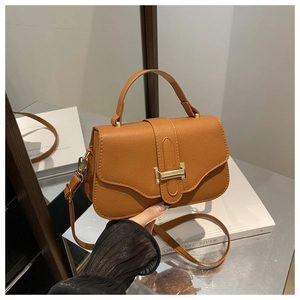 Detailed shot of brown faux leather shoulder bag with lychee texture and golden H-buckle