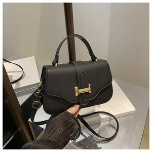 Close-up of black lychee grain leather handbag with iconic golden H-shaped buckle