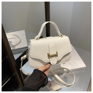 Detail of white lychee texture leather bag with elegant gold metal clasp and top handle