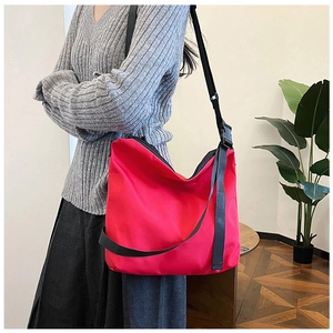 Détail du grand sac cabas rouge en nylon avec bandoulière noire ajustable sur un mannequin