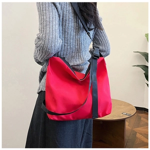 Vue détaillée du grand sac cabas rouge en nylon avec large bandoulière noire réglable