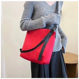 Détail du grand sac cabas en nylon rouge avec bandoulière noire sur mannequin de mode