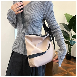 Détail d'un grand sac fourre-tout beige en nylon avec bandoulière noire sur modèle