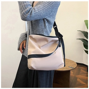 Sac croissant beige en nylon porté avec un pull gris et une jupe plissée noire élégante