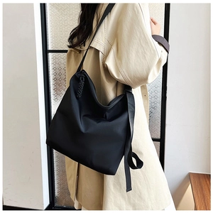 Détail de la sangle tissée sur un grand sac cabas noir minimaliste porté par un mannequin