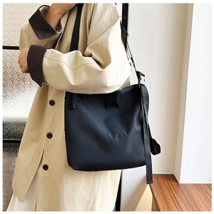 Vue détaillée du grand sac cabas noir en nylon porté par un mannequin en trench-coat beige