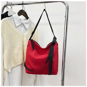 Détail du sac cabas en nylon rouge avec bandoulière noire réglable et boucle en plastique