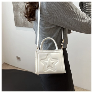 Detail of white leather shoulder bag with embossed large star design and top handle