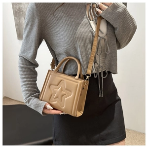 Detail of khaki square handbag showing star embossed design and adjustable shoulder strap