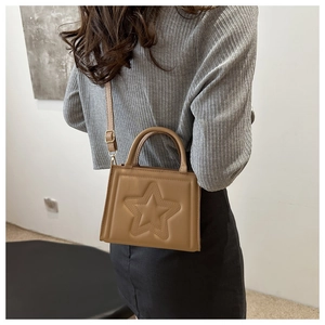Brown crossbody bag with star pattern embossing worn by model in minimalist setting