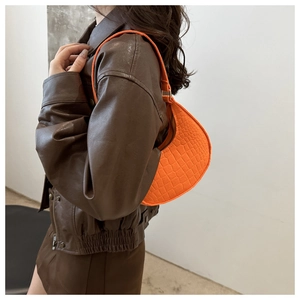 Detail view of orange crescent underarm bag with crocodile pattern and zipper closure