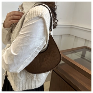 Detail of dark brown hobo bag with crocodile embossed texture and adjustable gold buckle