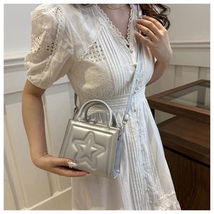 Silver metallic handbag with embossed star detail worn with a white lace dress