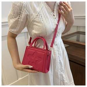 Hot pink mini tote bag with embossed star detail worn as a crossbody bag by a model
