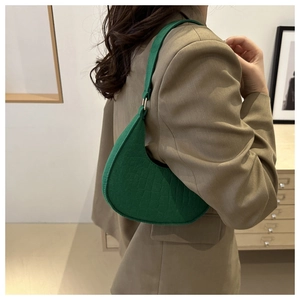 Detail of emerald green crescent bag with faux crocodile texture worn on shoulder