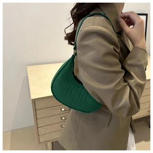 Side view of emerald green crescent hobo bag with embossed texture worn by a model