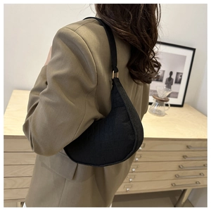 Model wearing black faux crocodile crescent bag with gold hardware in stylish interior