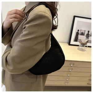 Detail of minimalist black crescent hobo bag featuring embossed texture and gold hardware