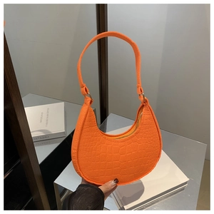 Detail of orange hobo bag featuring crocodile pattern texture and golden zipper