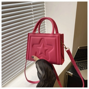 Detail of hot pink crossbody bag with embossed star pattern and top handle strap