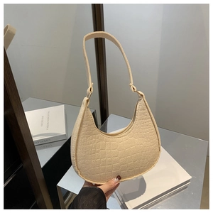 Close-up of beige faux crocodile skin texture on a half-moon shaped underarm handbag