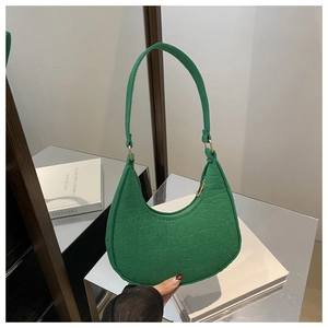 Detail of dark green crescent bag with crocodile pattern and golden metal ring accents