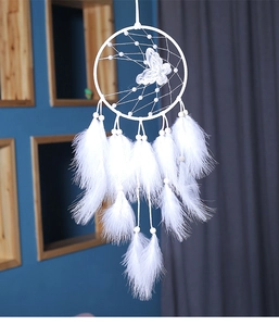 Detalle de atrapasueños blanco artesanal con mariposa de encaje y plumas decorativas